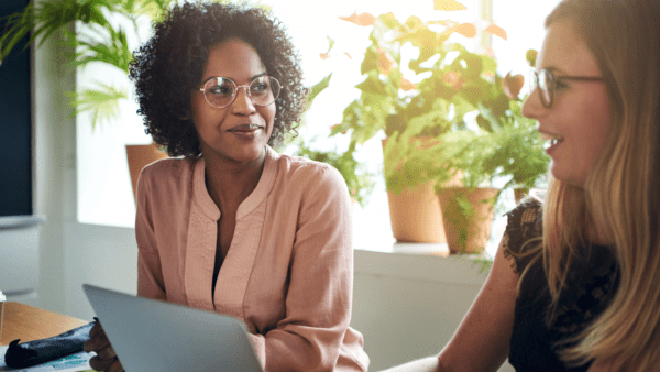 Black woman and white woman at laptop looking on